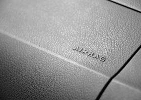 Detailed view of a leather car airbag label on a dashboard in black and white.