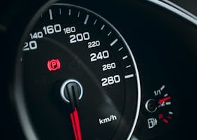 Detailed close-up of a speedometer with red needle indicating speed in km/h.
